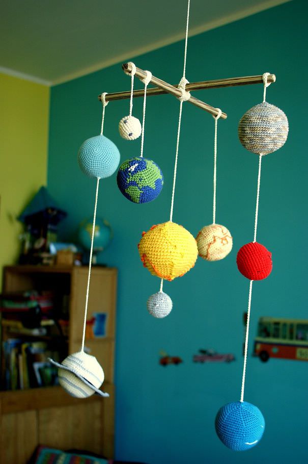 اتاق خواب کودکانه پسری که از سقف آن آویز سیاره های منظومه شمسی آویزان شده است